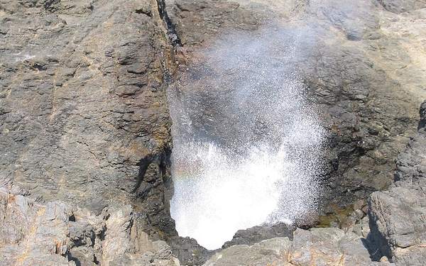 Spray bursting from the Kiama Blowhole through dark rock